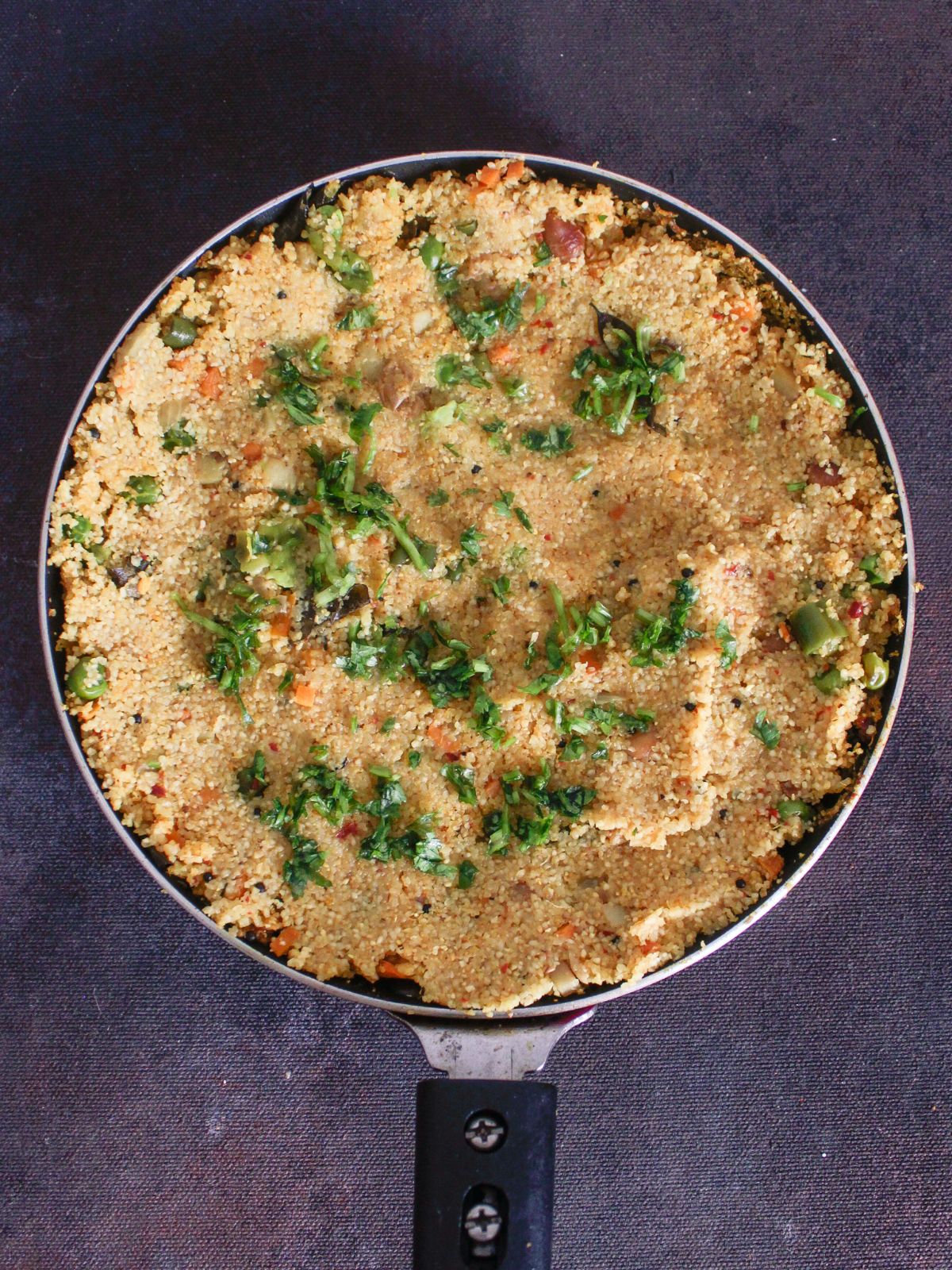 skillet full of cooked cream of wheat topped with fresh coriander