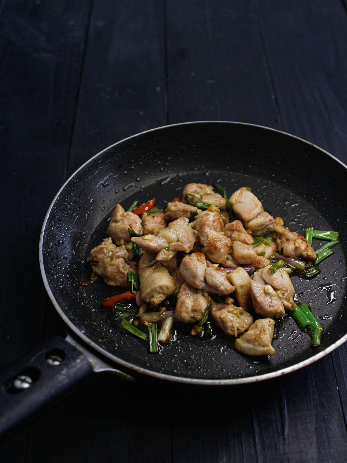 small black skillet with chicken and chiles on black table