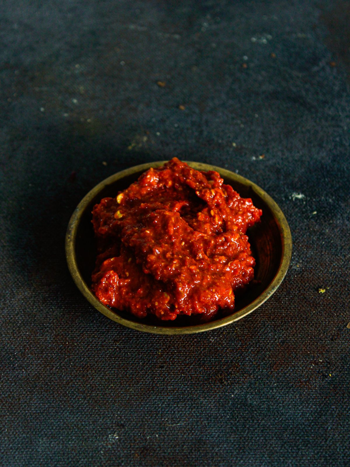 red spicy garlic chutney in gold bowl on black table