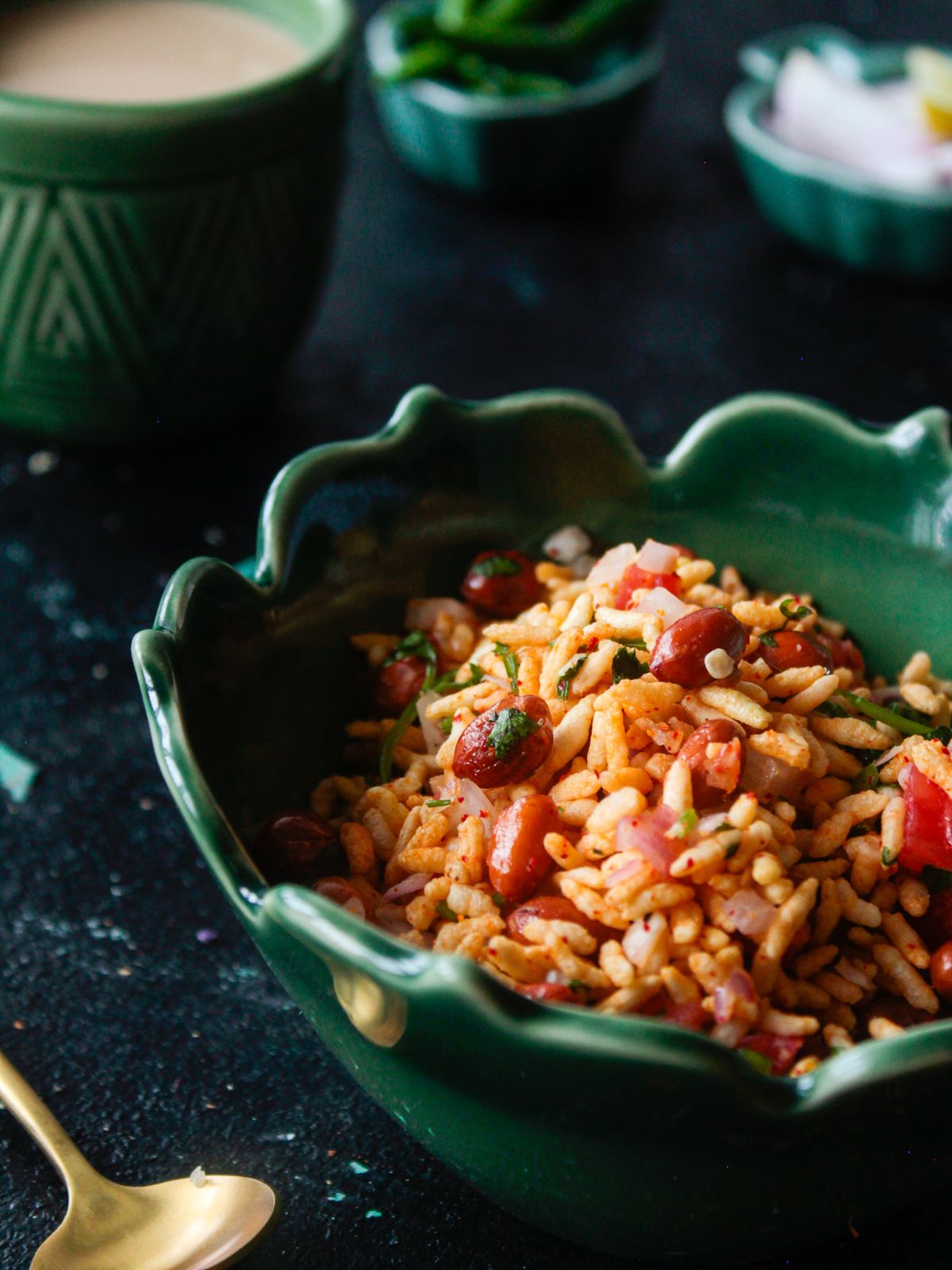 green bowl of jhaal muri on black table by gold spoon