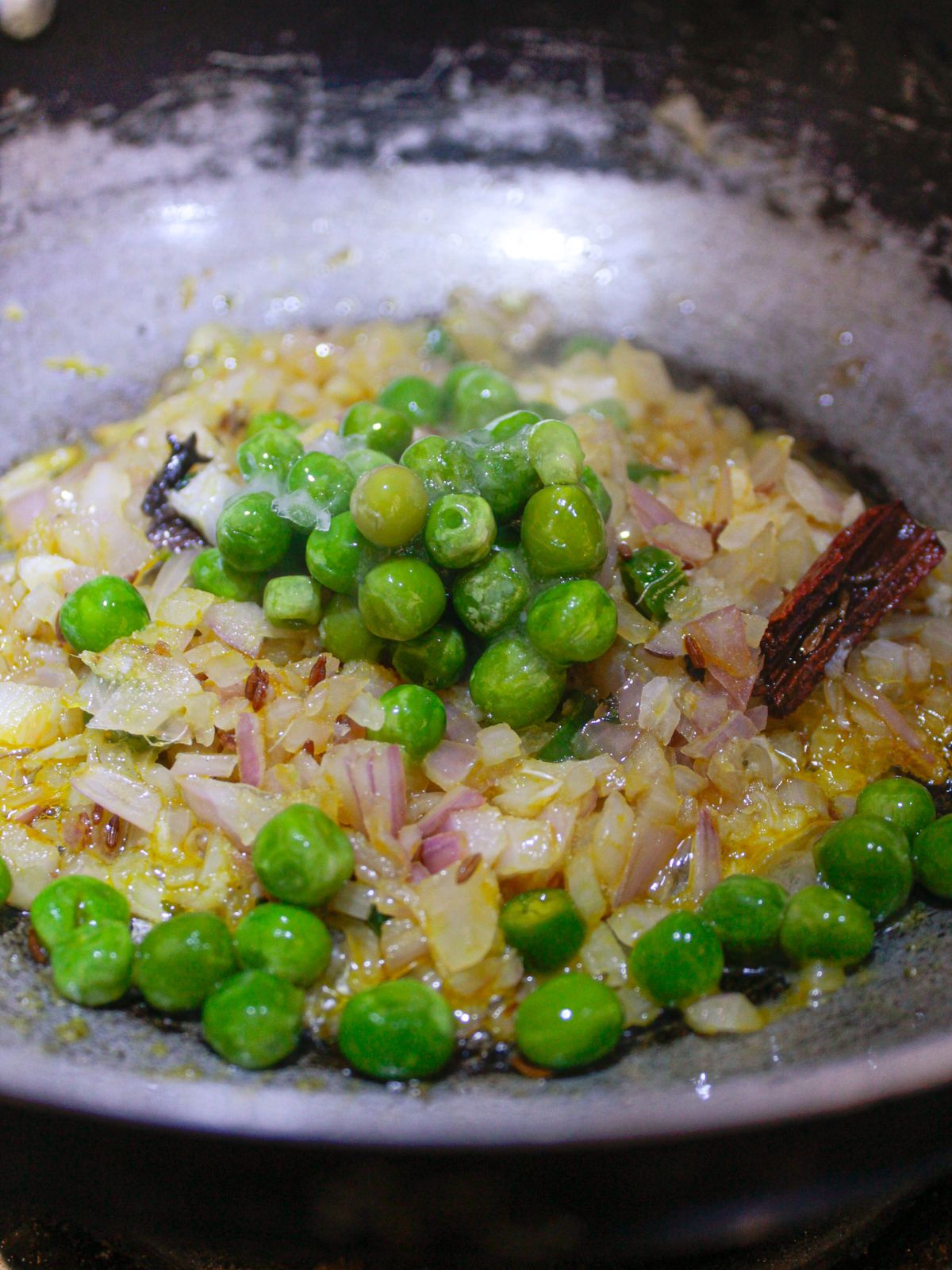 Green peas in skillet with cooked onions