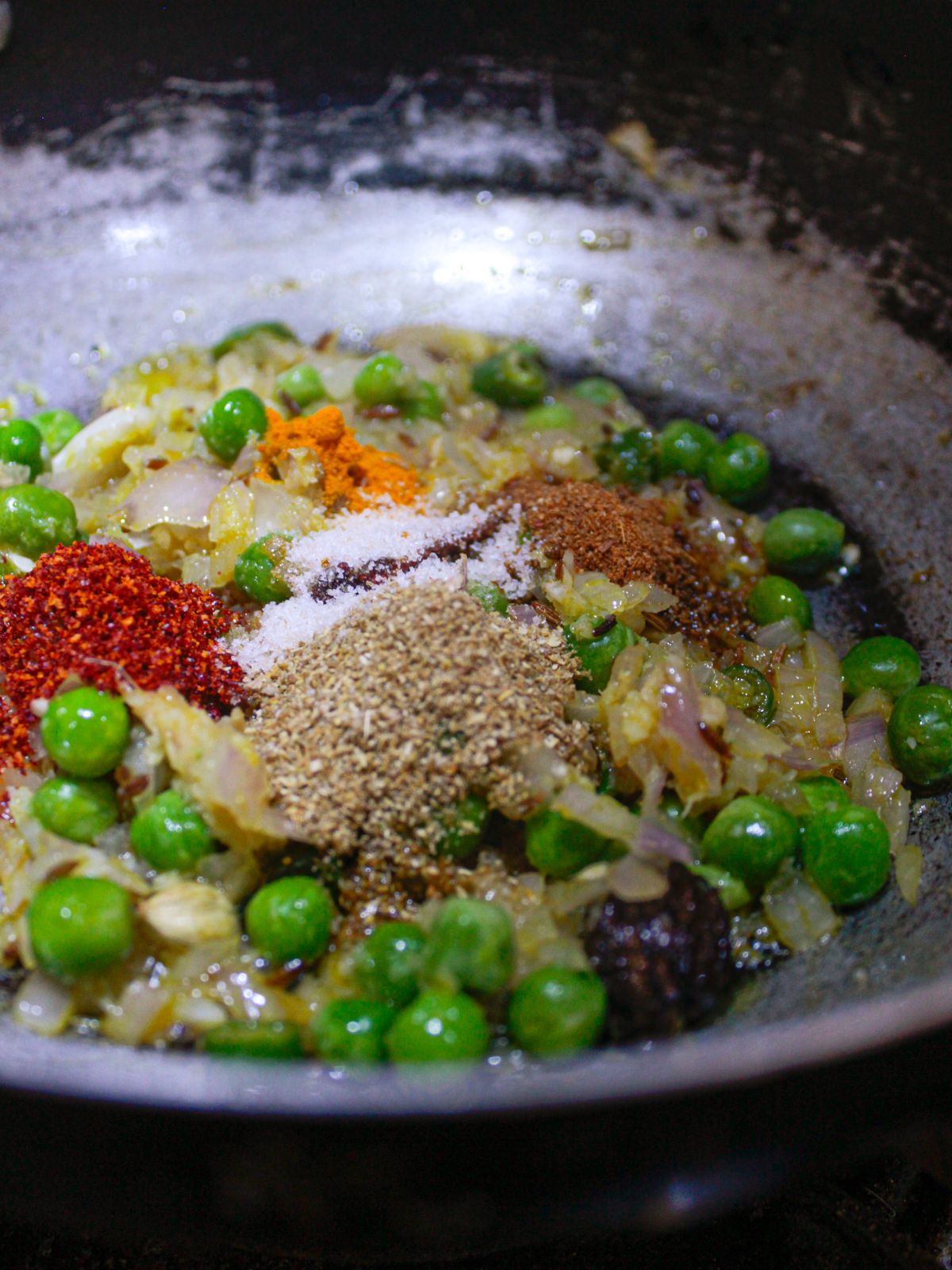 Dry spices on top of green peas and onion in skillet