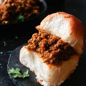 Bun filled with mutton curry on black plate