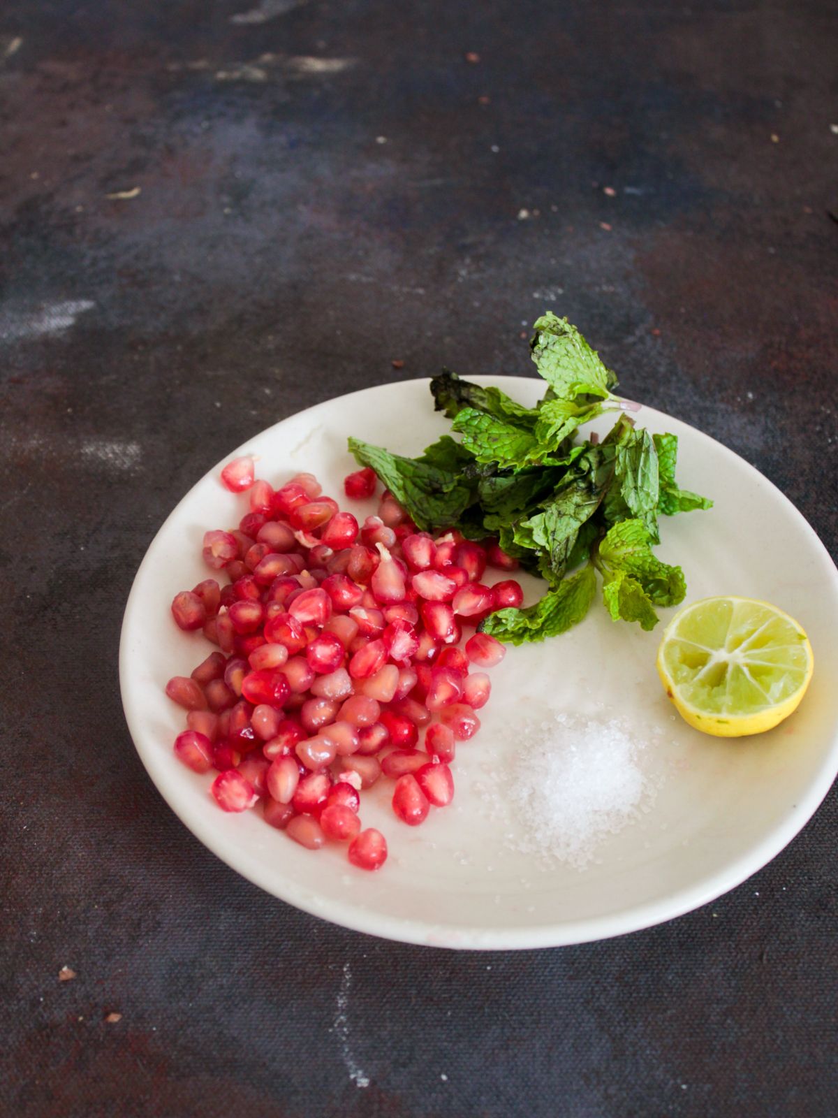 Ingredients for Pomegranate Mint Cooler on white plate