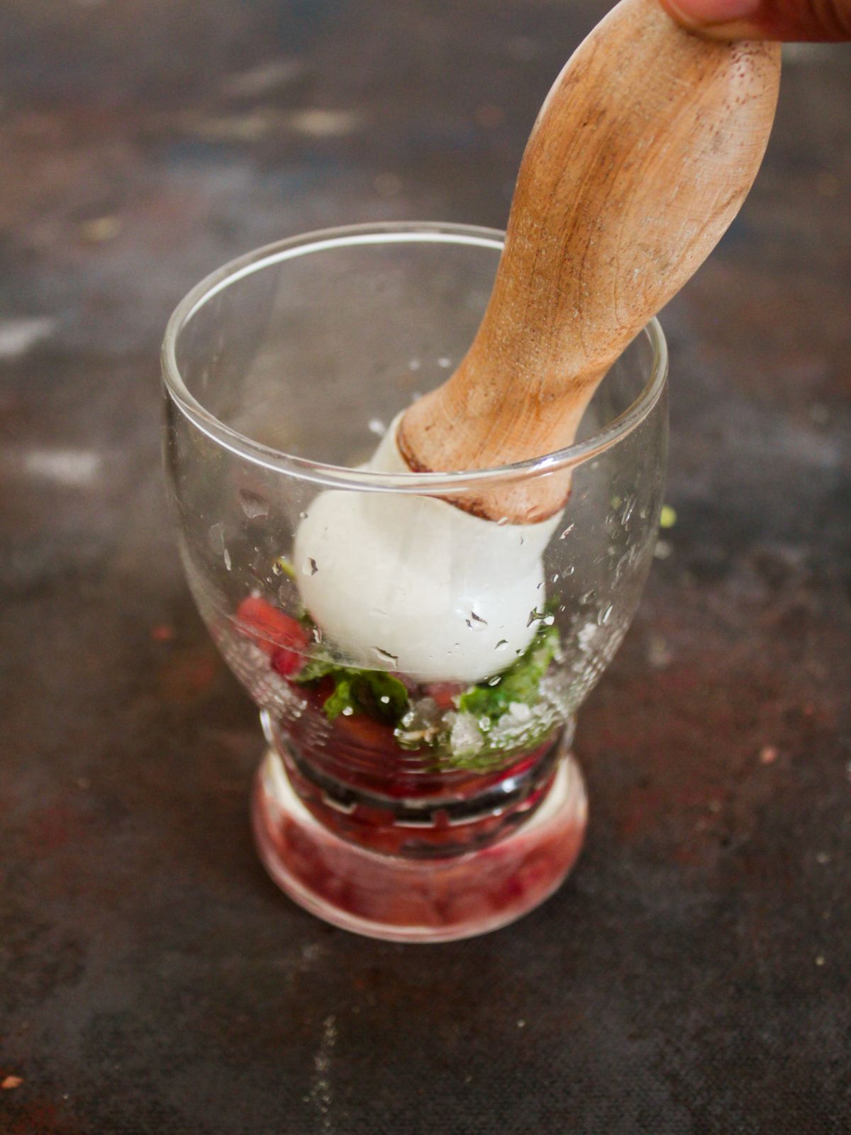 Wooden masher in glass with mint and pomegranate