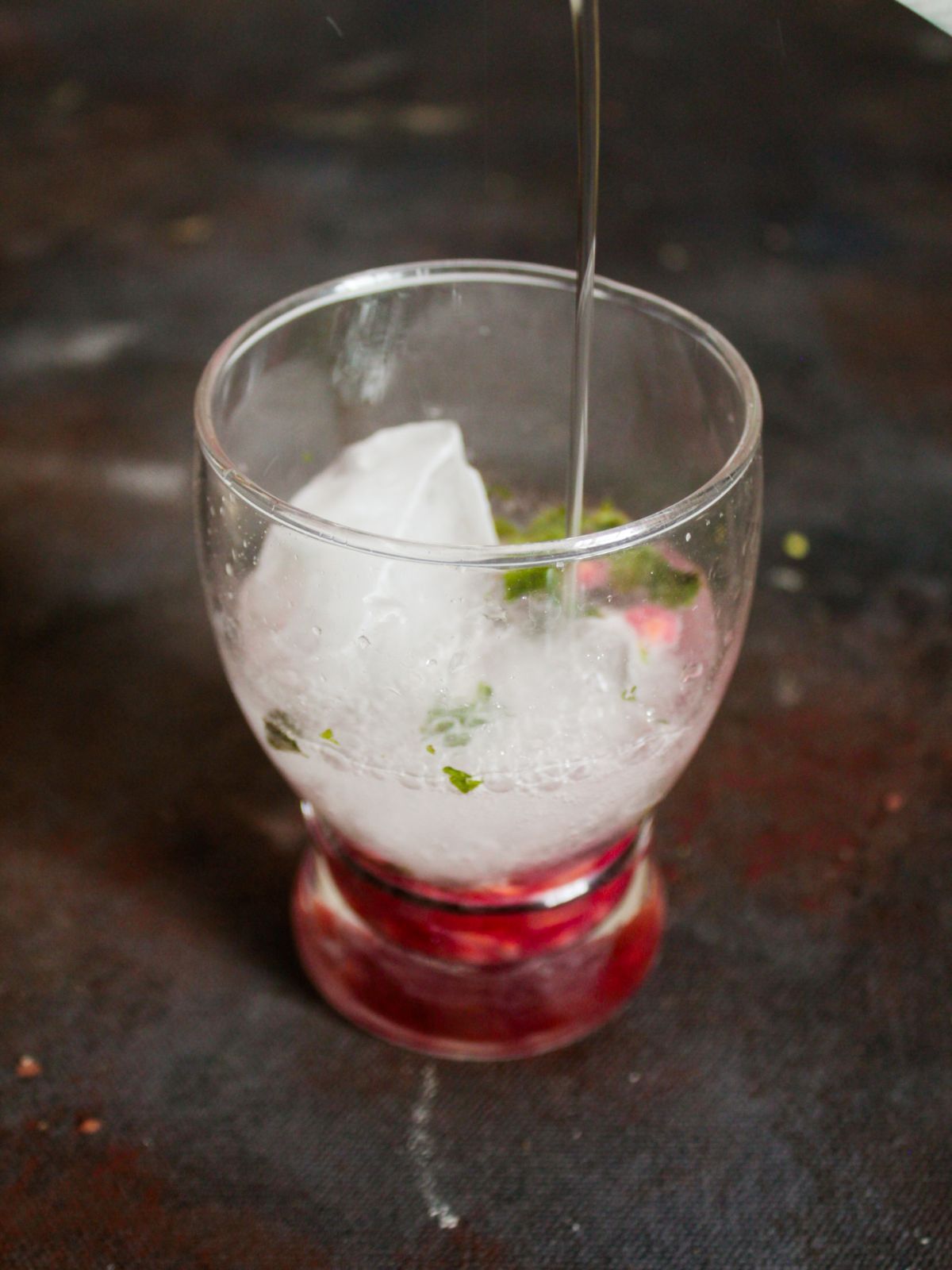 Adding ice to glass of pomegranate and mint