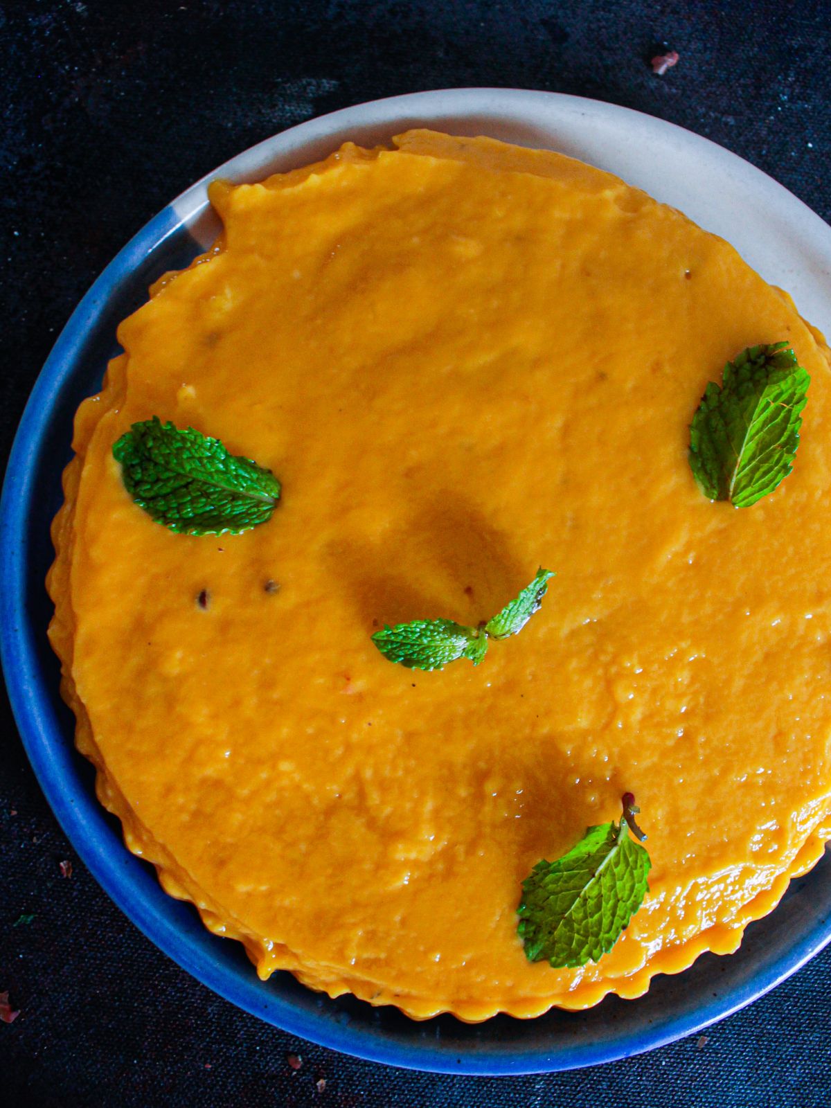 mango pudding on blue plate with mint leaves on top