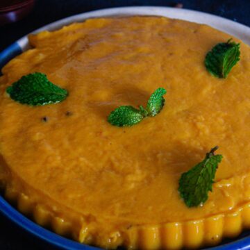 orange mango pudding on blue plate with mint leaves on top