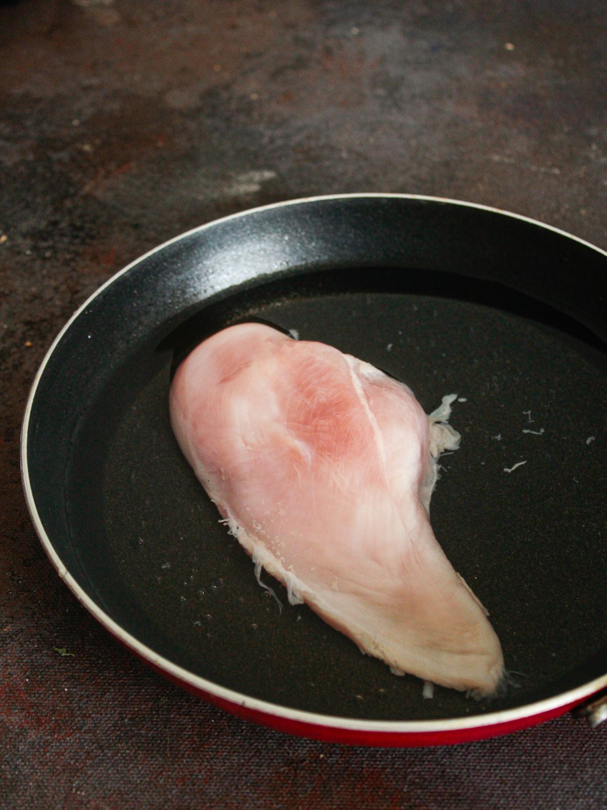 Raw chicken breast in pan
