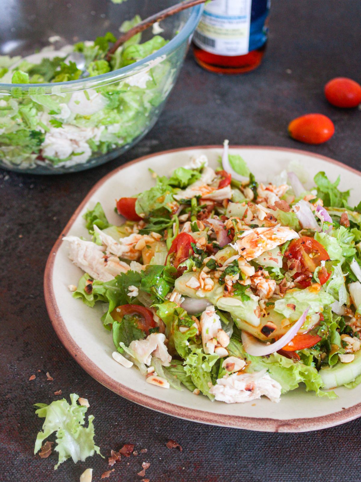 Thai chicken salad on plate by bowl of lettuce
