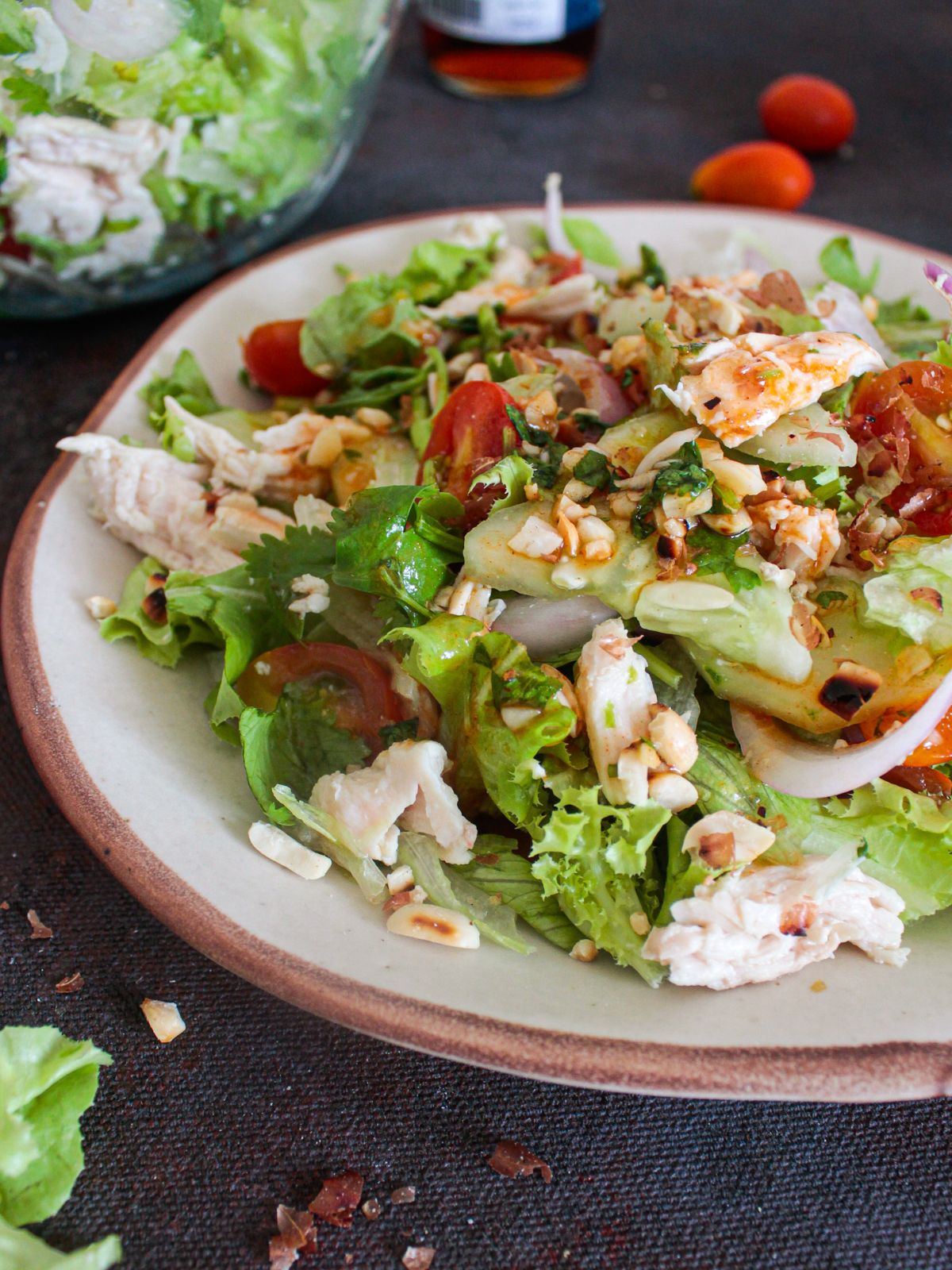 plate of salad with red peppers and chicken on black table