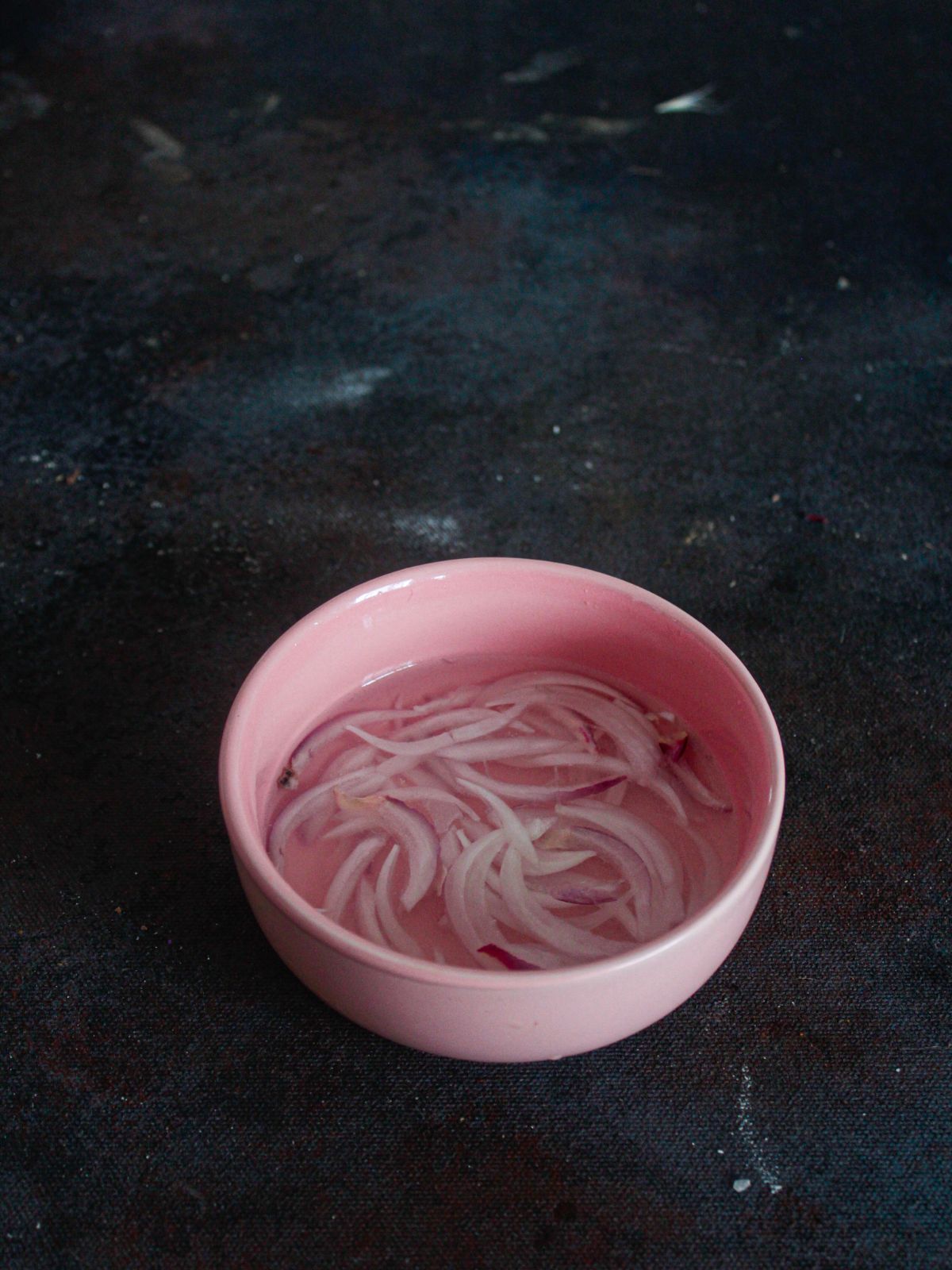 pink bowl of red onions in liquid