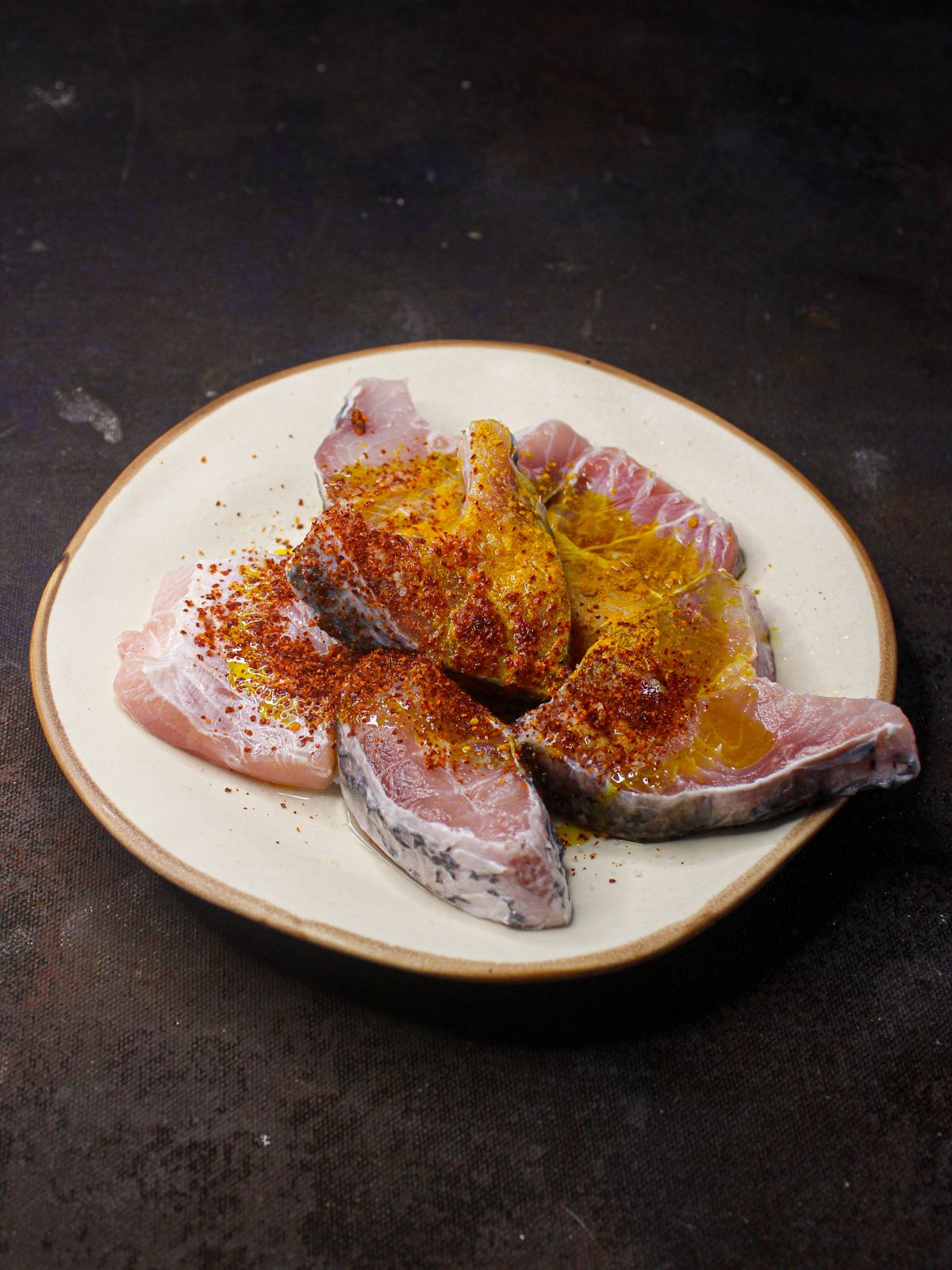 raw fish in seasonings on white plate