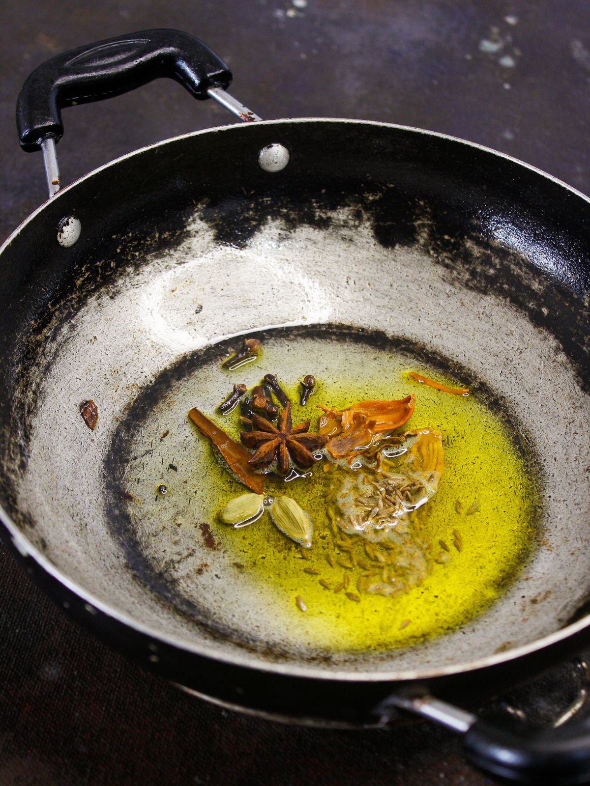 herbs and seeds in oil in skillet