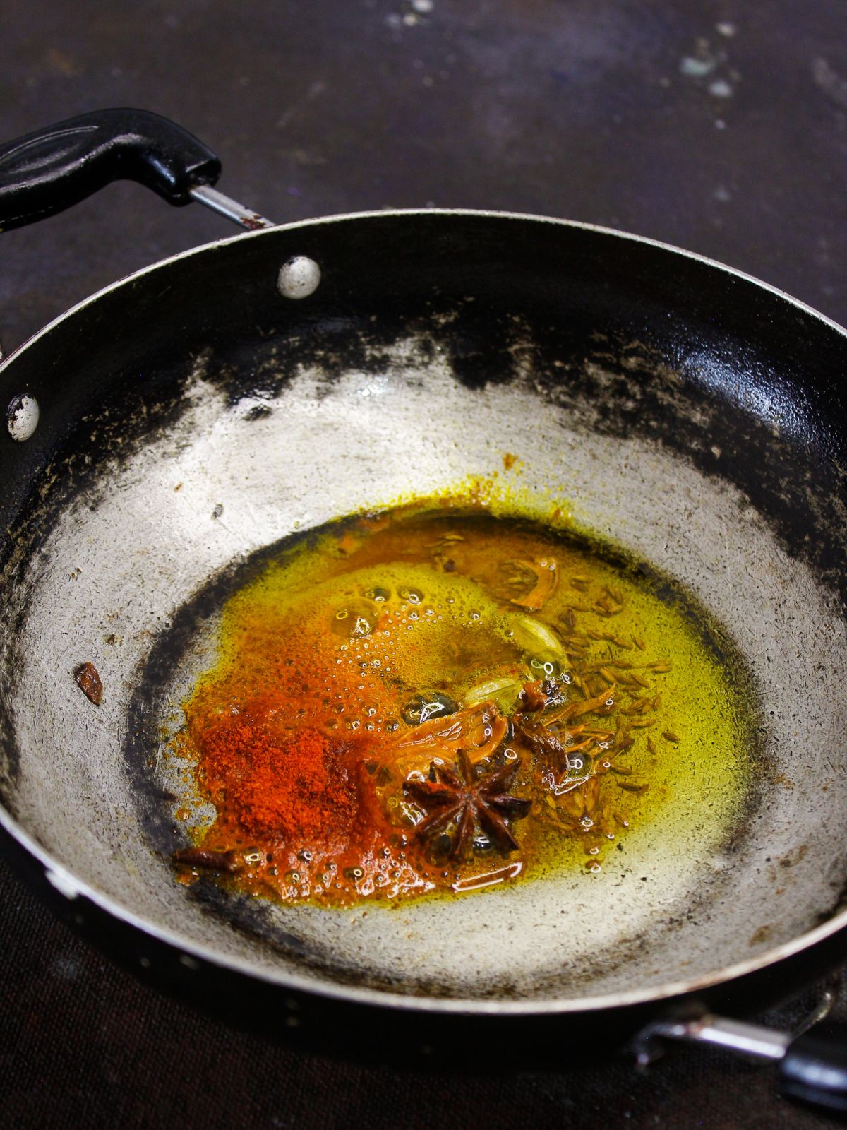 oil with herbs and spices in skillet
