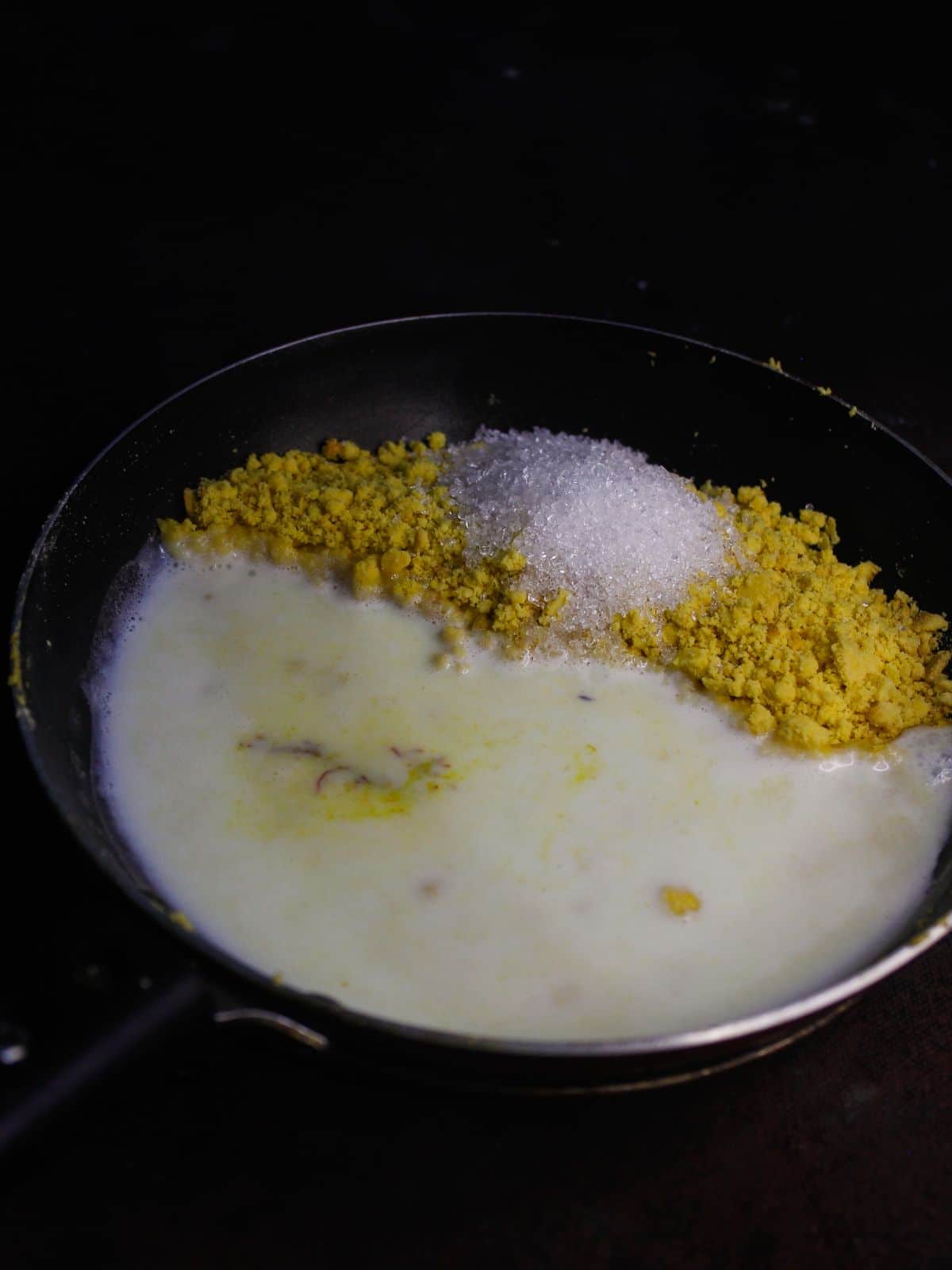 Add sugar, milk, kesar to the besan in a pan
