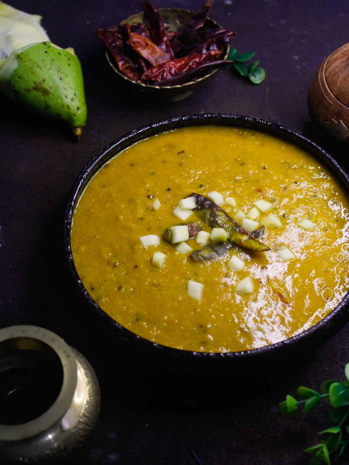 bowl of dal on table by silver bowl and dry chiles