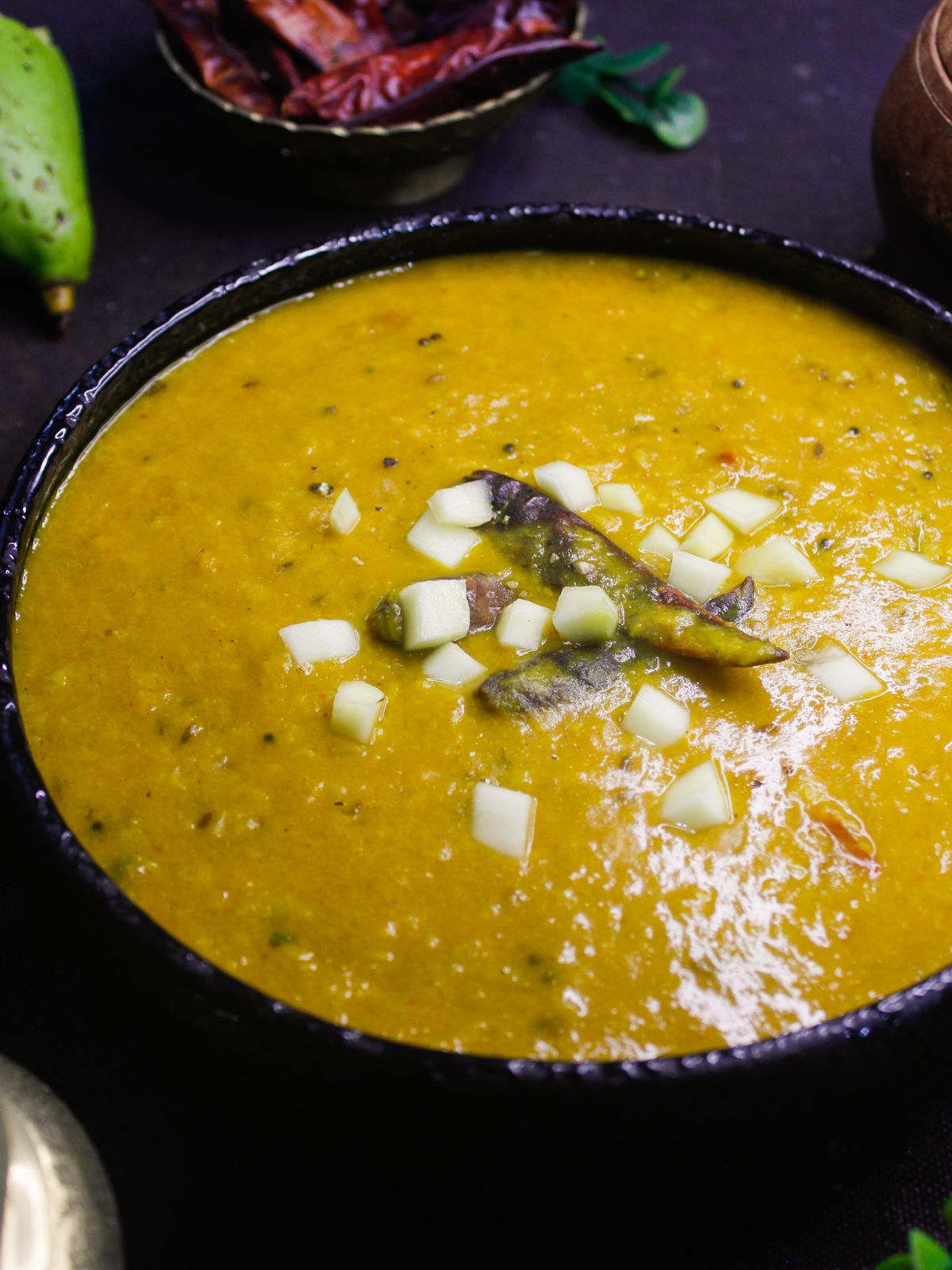 black bowl of mango dal topped with onion