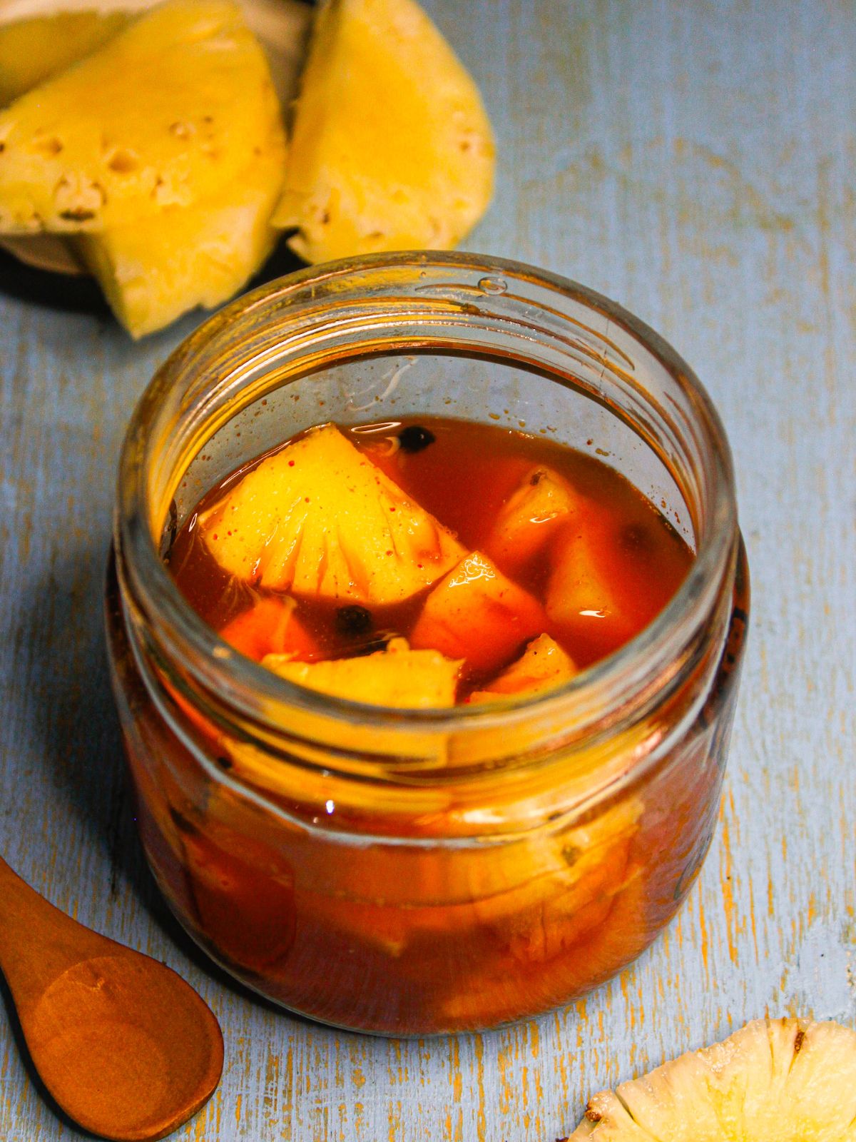 Pineapple Acharu: Sri Lankan Pineapple Pickle served in a jar with raw pineapple pieces in the background