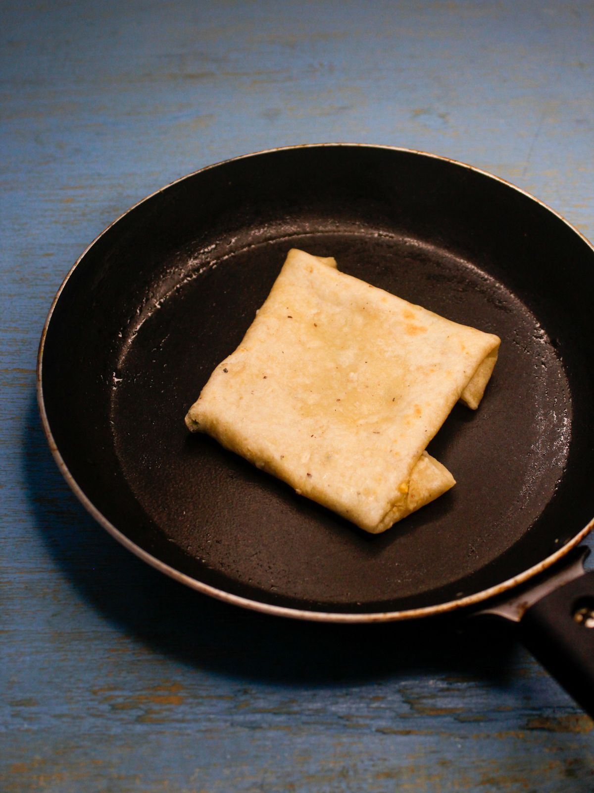 fold the sides of the roti making it a square and flip it so that it is  cooked on both the sides