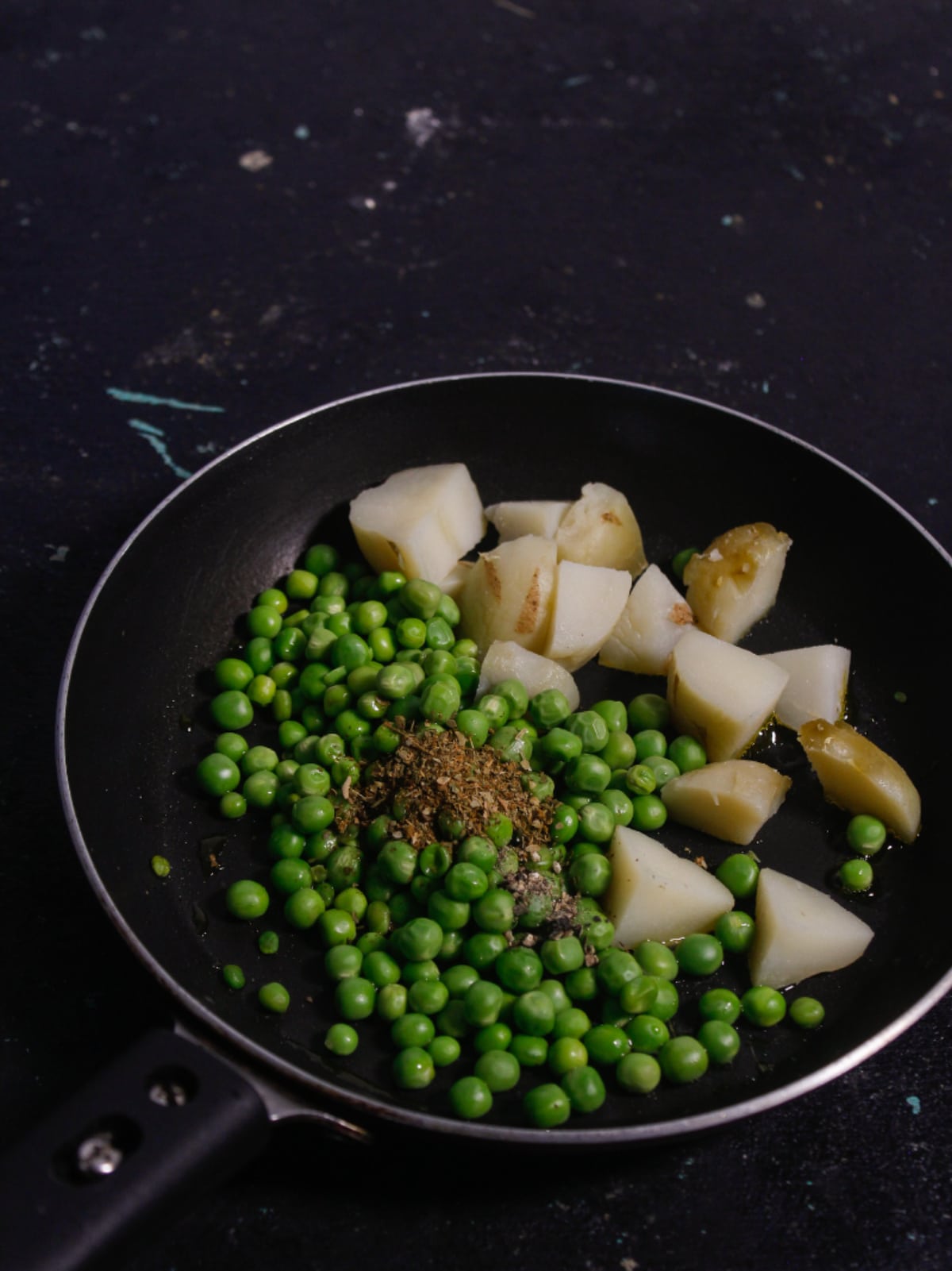 Blanch peas and cubed potatoes with spices in a pan